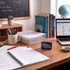 Teacher’s desk with laptop, digital clock, notebooks, pens, and classroom books