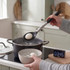 Salter kitchen timer beside boiling eggs in pot and slotted spoon with egg.