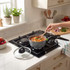 Grey non-stick saucepan on gas hob, cooking vegetable pasta in a modern kitchen setting