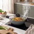 Non-stick wok with glass lid steaming noodles and vegetables on induction hob