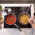Cooking hob with two pans, one has tomato sauce, the other boiling pasta nests