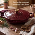 Red cast iron casserole dish with meatballs being served, oven gloves visible