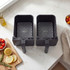 Dual black air fryer baskets on kitchen counter, shown empty from above
