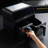 Black double drawer air fryer with hand opening left basket, kitchen counter background