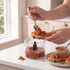 Spoon spreading tomato bruschetta topping on toast, food processor bowl in foreground