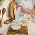 Handheld blue electric whisk mixing ingredients in glass bowl on kitchen worktop