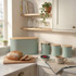 Sage green kitchen canisters and bread bin with bread loaf and tea, in cosy kitchen setting
