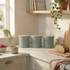 Set of sage green kitchen canisters with wooden lids on countertop, one with tea bags