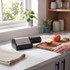 Electric knife sharpener in black with a stainless steel panel, shown sharpening a knife