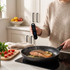 Digital thermometer checking cooked salmon fillet in frying pan with herbs and lemon slices