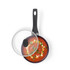 Black non-stick saucepan with lid, top view, filled with tomato soup and herbs