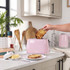 Pink two-slice toaster on kitchen counter with hand removing toasted bread