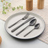 Set of matte black cutlery arranged on white plate