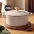 Cream cast iron casserole dish serving vegetable stew, with bowls and bread roll.