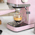 Pink espresso coffee machine making a fresh espresso into a glass cup.
