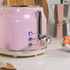 Pink 2-slice toaster with chrome accents, showing cancel, reheat and defrost buttons