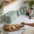 Green bread bin and canisters on kitchen counter, hand buttering sliced bread.