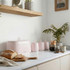 Set of pink kitchen storage tins with bread bin on marble worktop