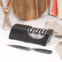 Electric knife sharpener with three slots, black and silver, shown on kitchen worktop
