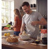 Person using electric hand mixer to knead dough with flour and ingredients on kitchen counter