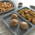 Product photo showing grey oven tray set with baked potatoes, chicken wings and chips.
