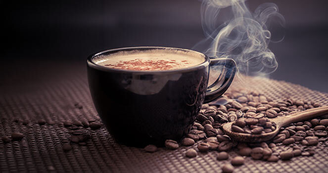 A Cup of biscoff mocha on a table with coffee beans