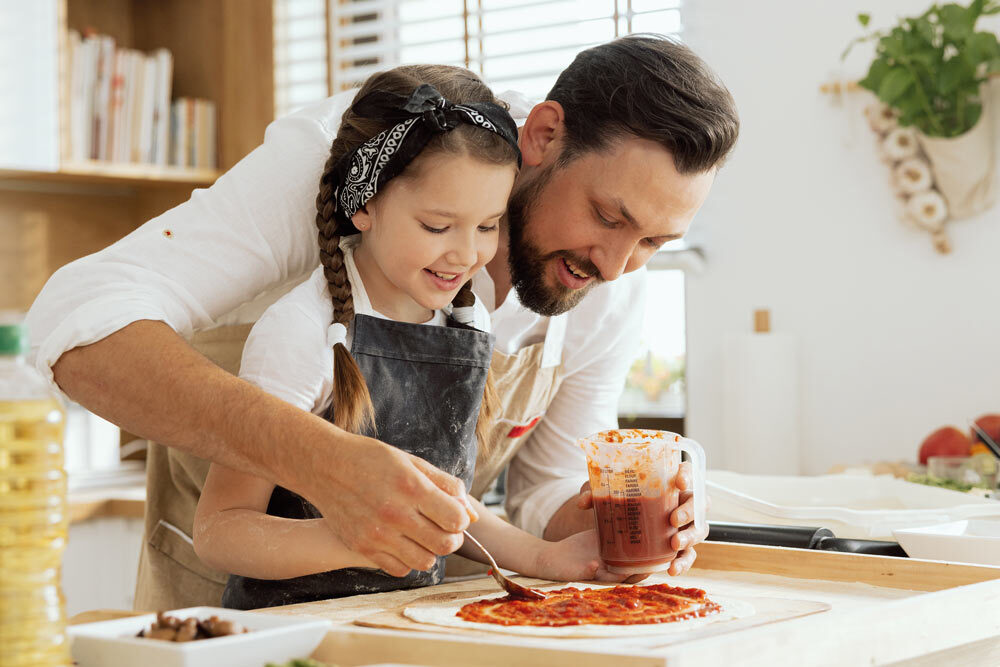 Father and daughter making pizzas together