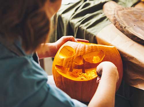 A woman carving a face into a Pumpkin