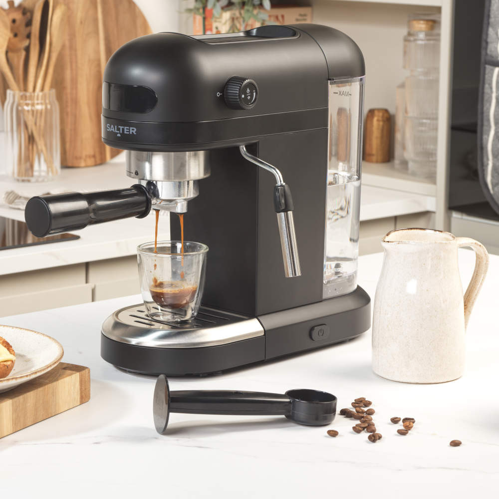 Black espresso coffee machine making coffee in a glass cup on kitchen counter