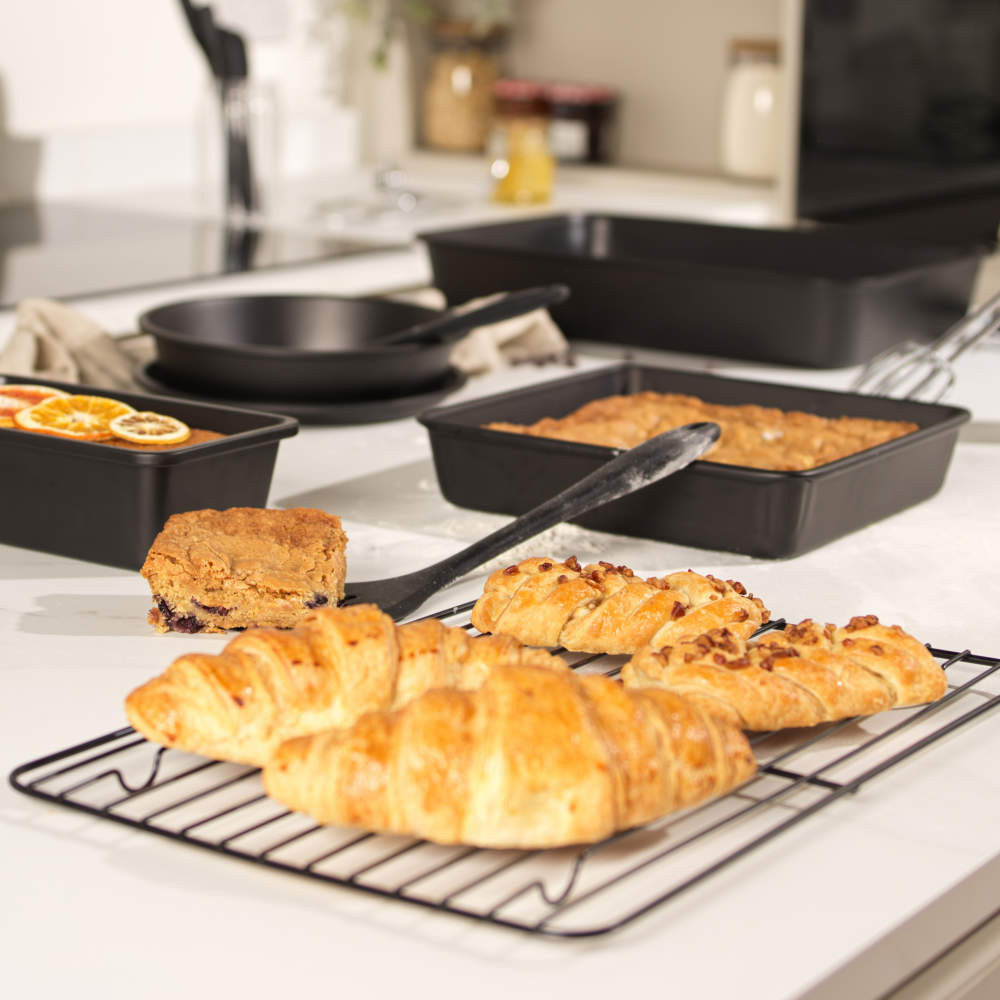 Set of non-stick black bakeware with pastries and traybake shown in a kitchen setting