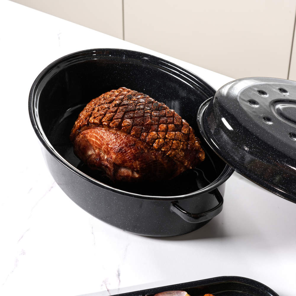 Roast joint in black enamel roasting pan with lid, shown on kitchen worktop