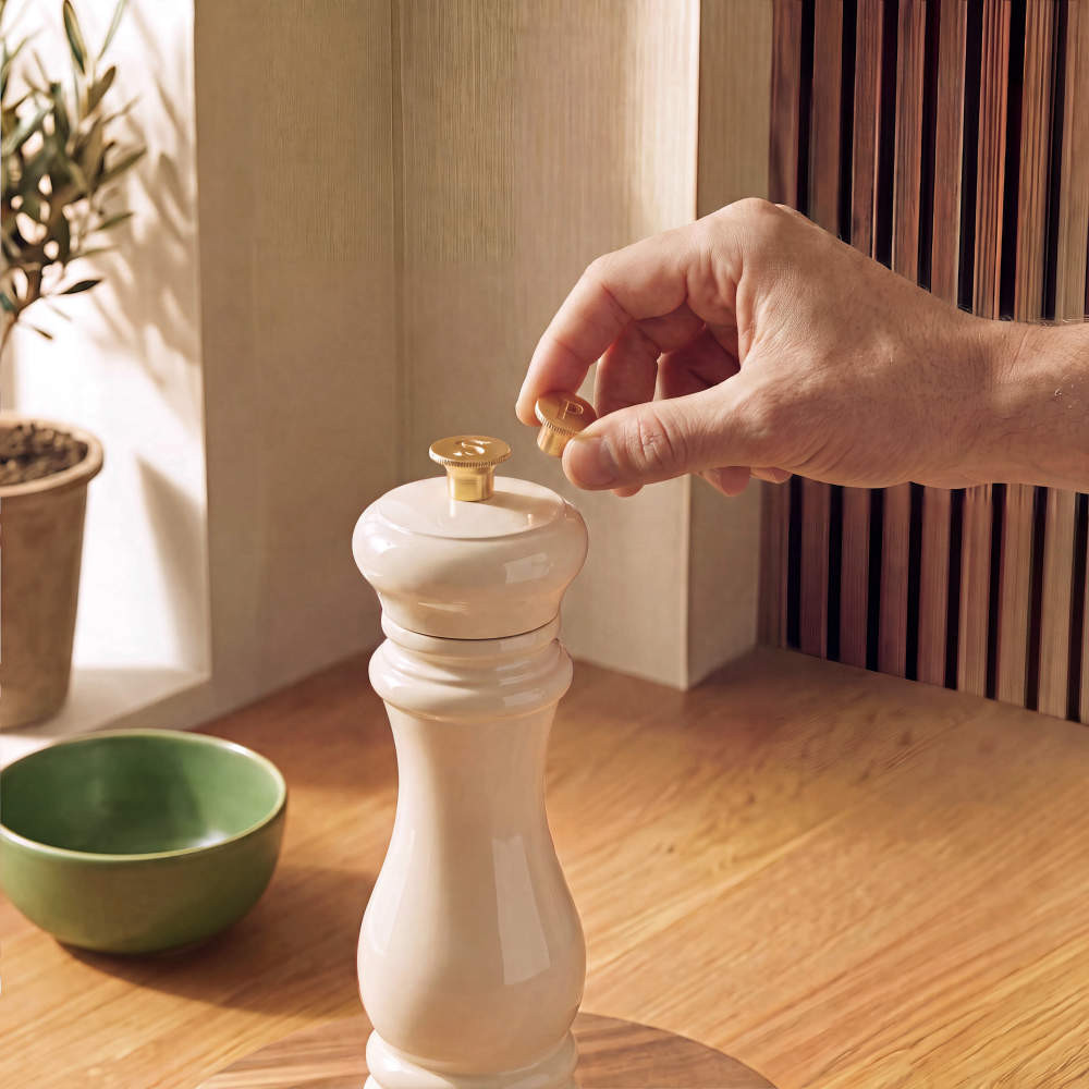 Cream pepper mill with gold top on wooden kitchen worktop