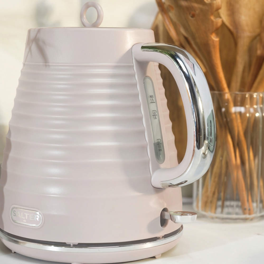 Pink ribbed electric kettle with chrome handle on kitchen countertop