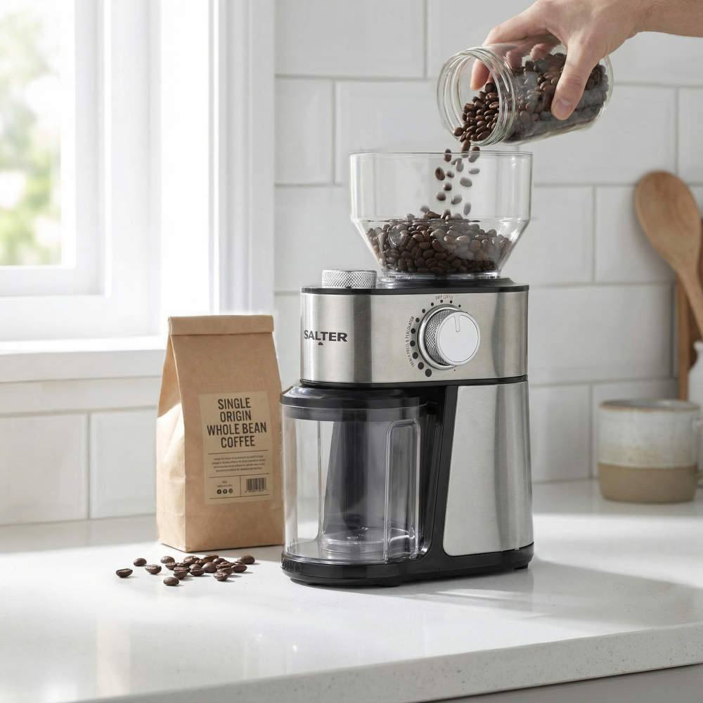 Electric coffee grinder in brushed steel. Whole beans being poured in. Kitchen scene.