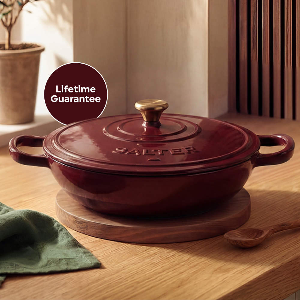 Red cast iron casserole dish with lid and gold handle, shown with Lifetime Guarantee badge.