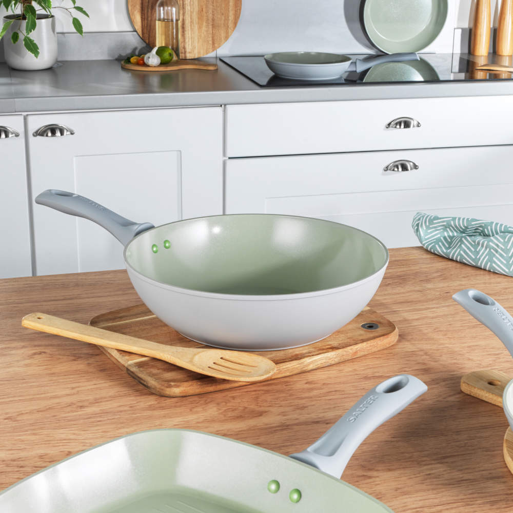 Green non-stick wok with grey handle on kitchen worktop