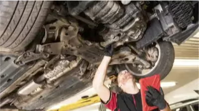 man looking at vehicle undercarriage