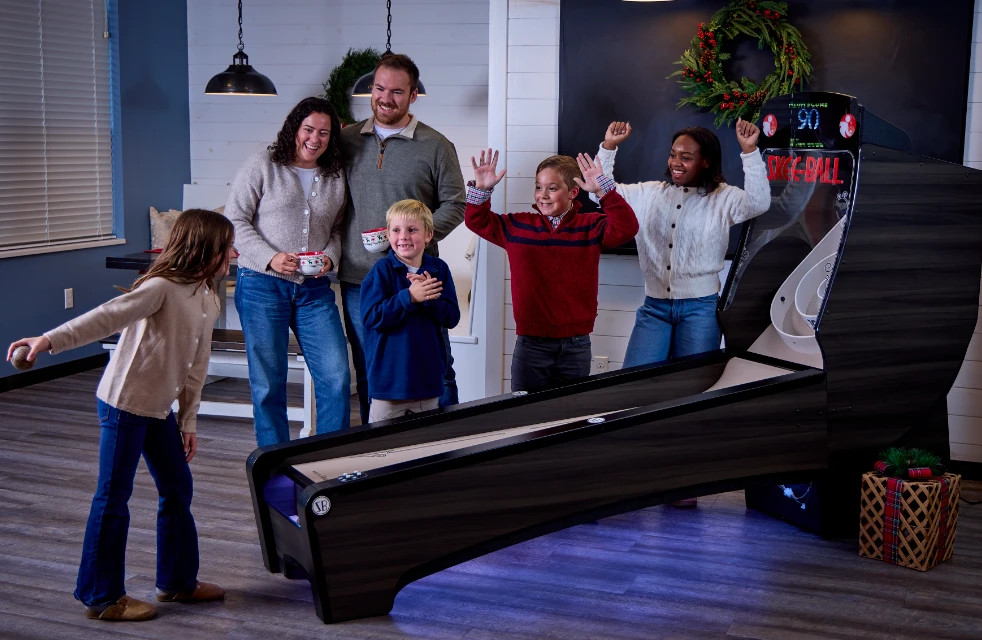 Family celebrating around a Skee-Ball alley in a festive living room