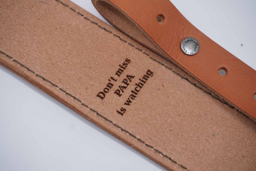 Personalized engraving on the back of a leather rifle sling showing a custom hunting quote.