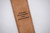 Custom engraved dedication message on the back side of a leather rifle sling pad.