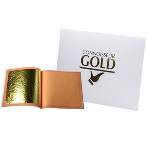 An open booklet of Connoisseur Gold Edible 23ct Gold Leaf showing one gold sheet, alongside white packaging with gold lettering and logo. An open booklet of Connoisseur Gold Edible 23ct Gold Leaf showing one gold sheet, alongside white packaging with gold lettering and logo.