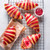 Five croissants with bold red raspberry stripes, resting on a cooling rack with a dish of raspberry jam and one cut open to reveal the fruity filling.