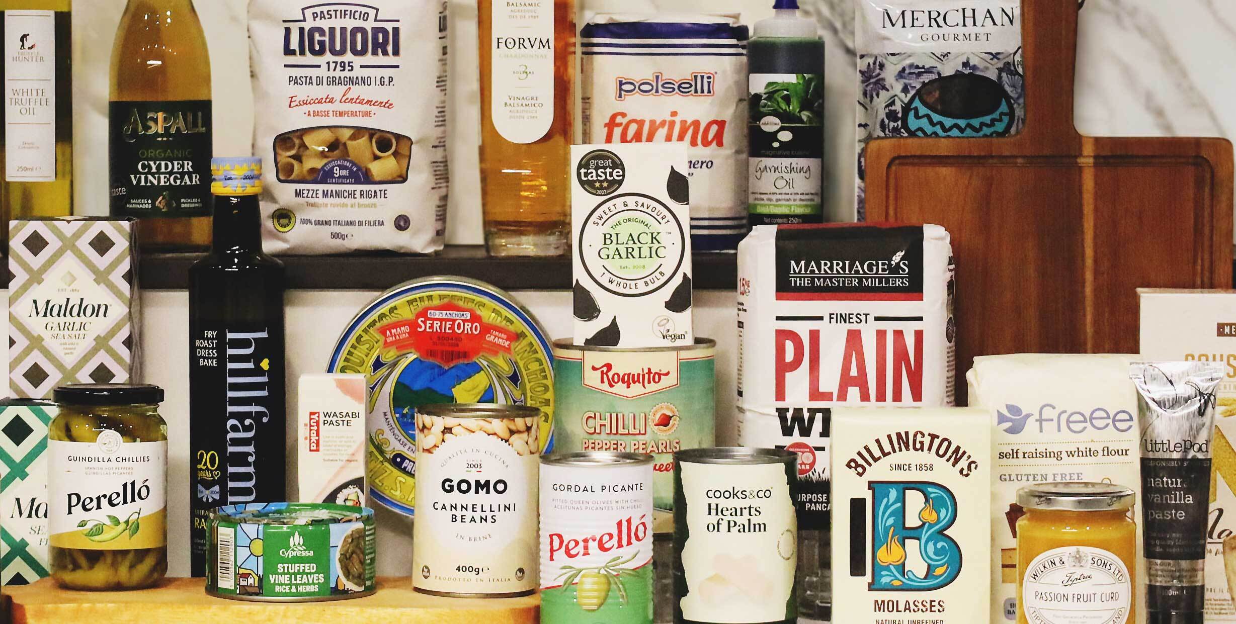 Selection of premium pantry ingredients including Perello olives, Liguori pasta, Maldon sea salt, Billingtons molasses, black garlic, flour, vinegars and speciality oils on kitchen counter for Infusions4Chefs online shop