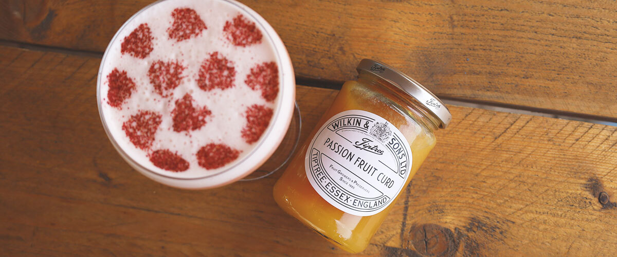 Tiptree passion fruit curd alongside a passion fruit martini with freeze dried raspberry dusting
