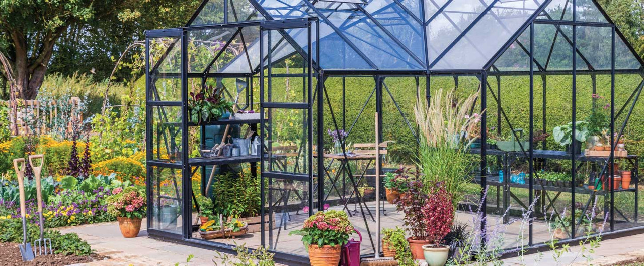 A greenhouse built in a garden with lots of plants