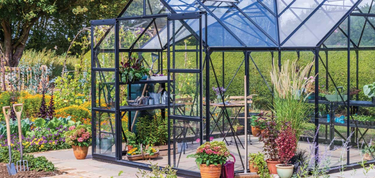 A greenhouse built in a garden with lots of plants