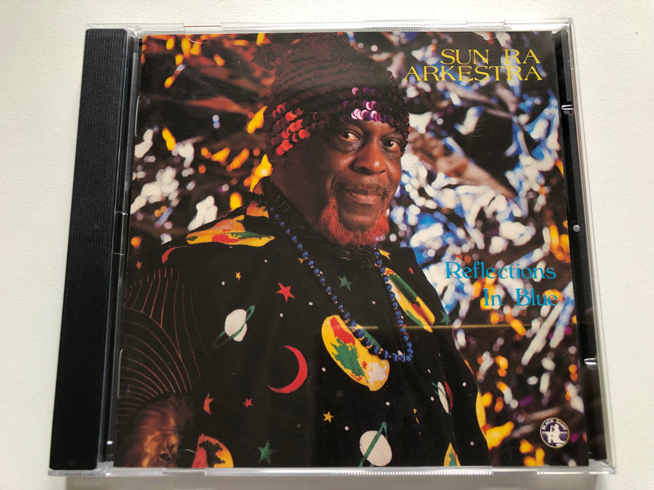 https://cdn11.bigcommerce.com/s-62bdpkt7pb/products/63279/images/320585/Sun_Ra_Arkestra_Reflections_In_Blue_Black_Saint_Audio_CD_1987_120101-2_1__68531.1704567203.1280.1280.JPG?c=2