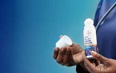 A person holding a bottle of the Pain Relief Liquid Roller.