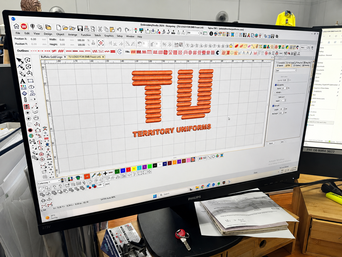 A customer logo on screen beside the finished stitch-out on fabric.