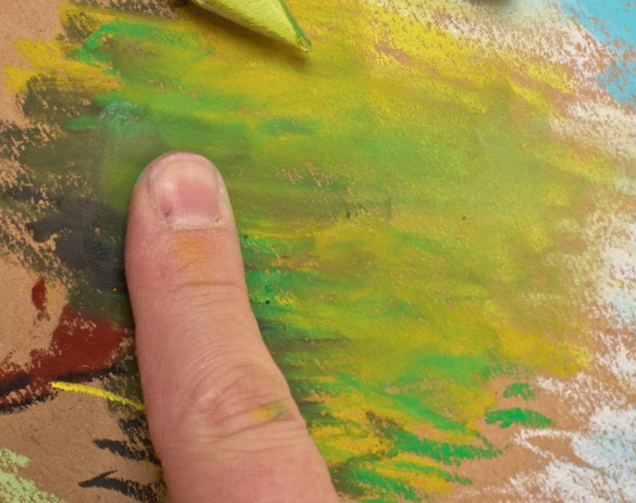 Blending green Caran d’Ache Neopastel oil pastel on toned paper with fingertip for soft landscape effects